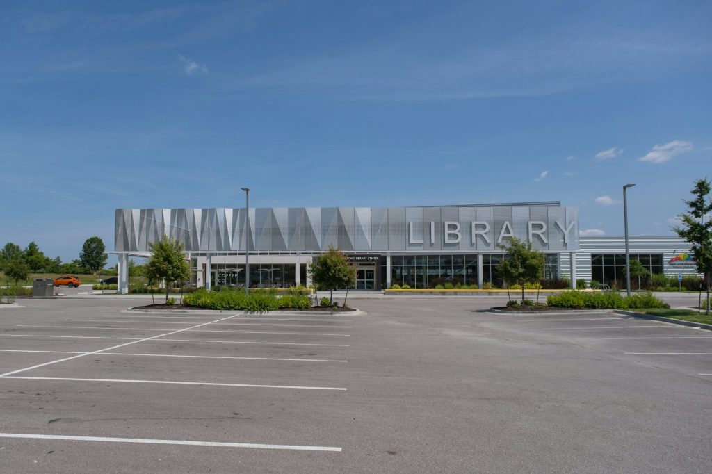 A modern library building in a suburban plaza setting, generic stand-in for the future Barrhaven facility