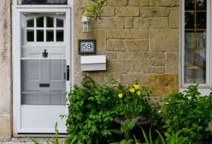 Stone house with a white front door and yellow tulips