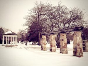 A stone-pillared gazebo in a snowy park