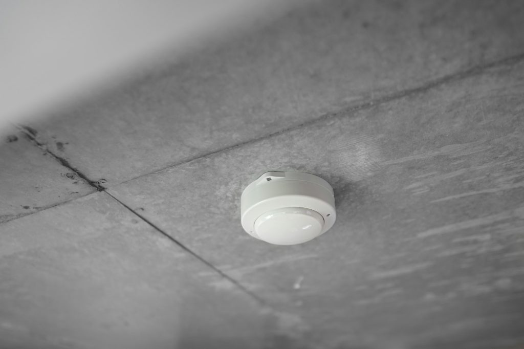 A round white alarm mounted on a ceiling
