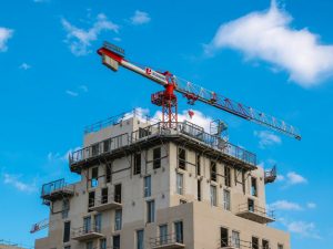 A construction crane beside a tall building under construction against a blue sky